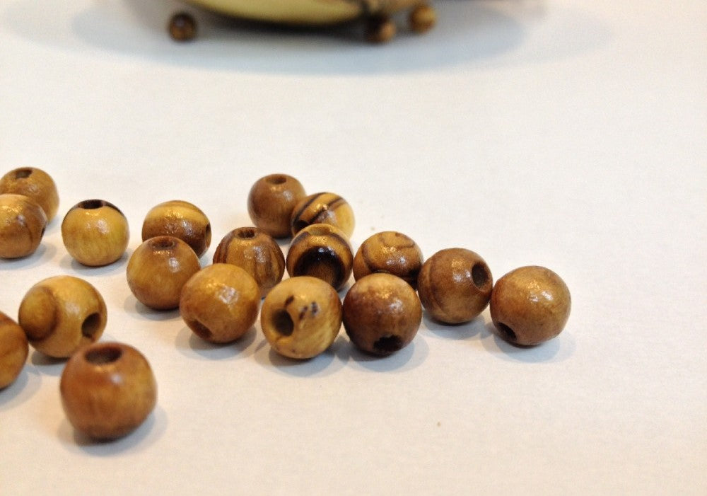 A Few 6mm Bethlehem Round Olive Wood Beads On Table.